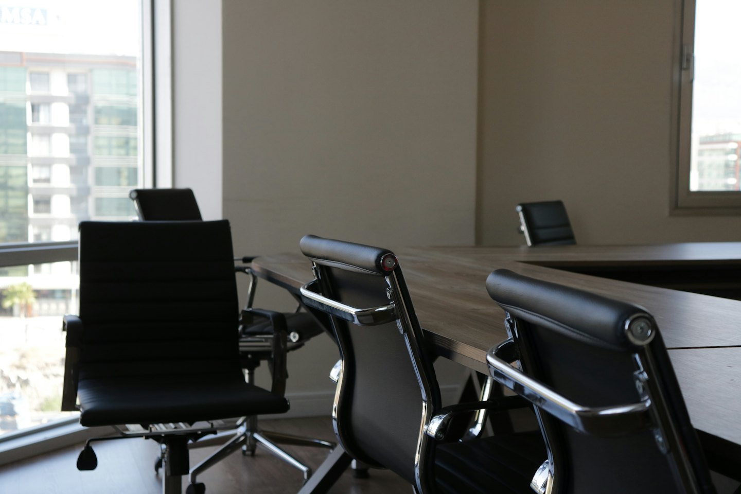 Empty modern conference room with light wood table and black chairs.